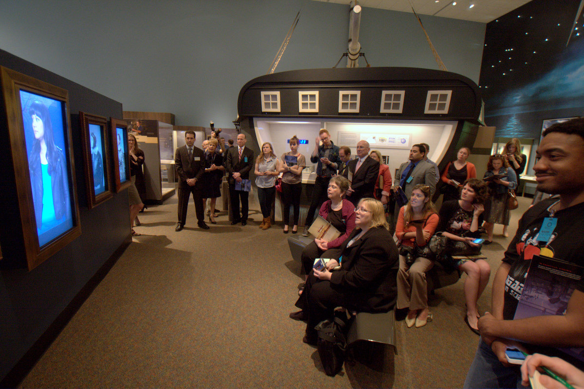 Press visitors watch "video portraits" of actors portraying users of naviation throughout history. (click image for a larger view) 