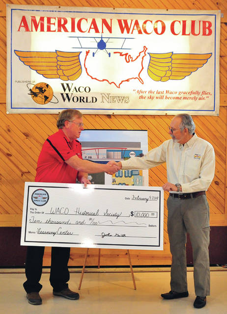John Gerth, right, president of the American WACO Club, based in Indianapolis, presents a check in the amount of $10,000, to WACO Historical Society President John Schilling during a ceremony at the WACO Museum and Learning Center in Troy on Friday.